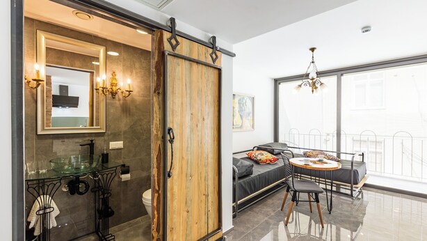 A modern bathroom with a glass sink, a wooden wardrobe, a black metal stand, and a large window with a view. - Villa Pera Suite Hotel (Istanbul)