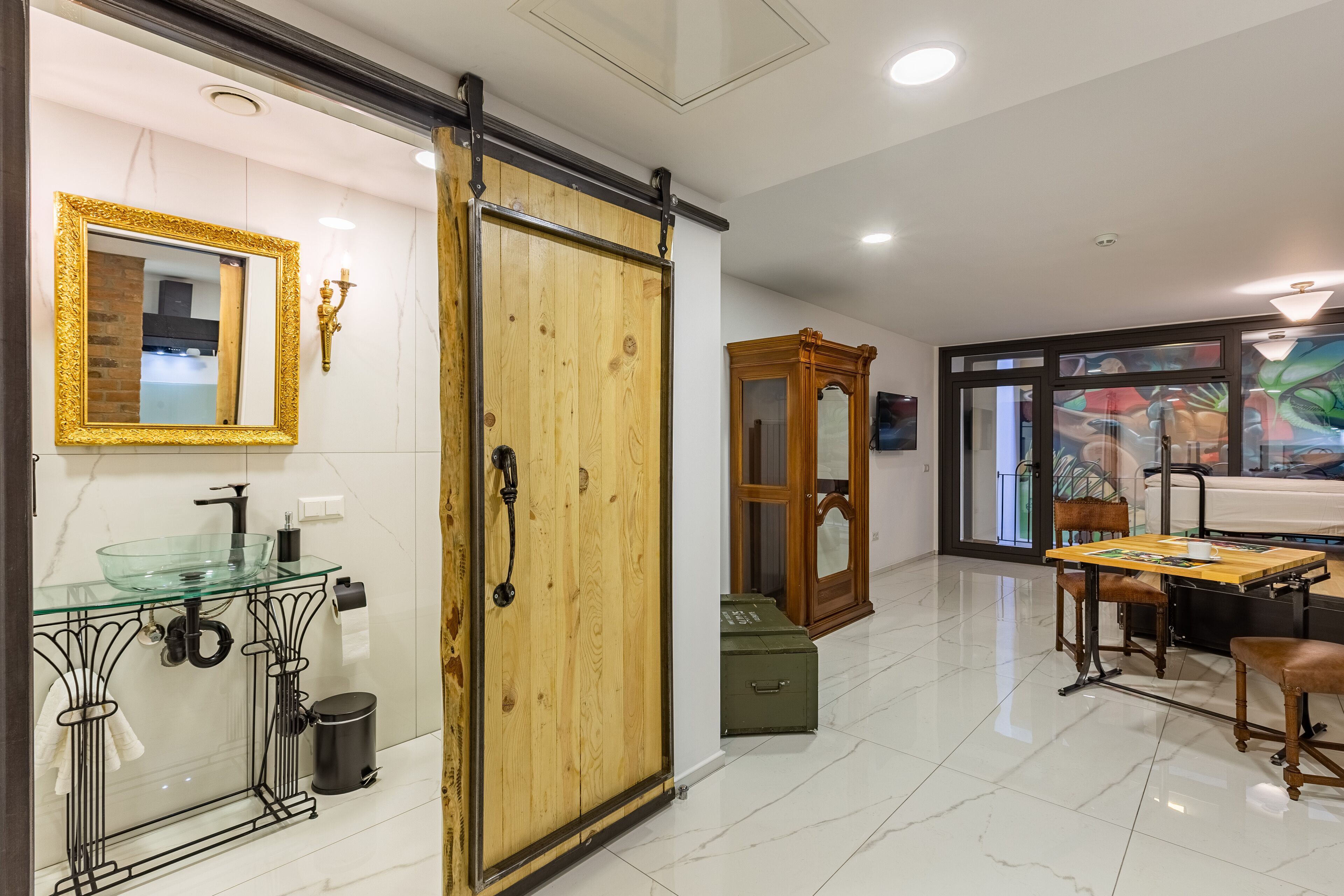 A modern kitchen with a glass-top sink, wooden cabinets, and a sliding door.
