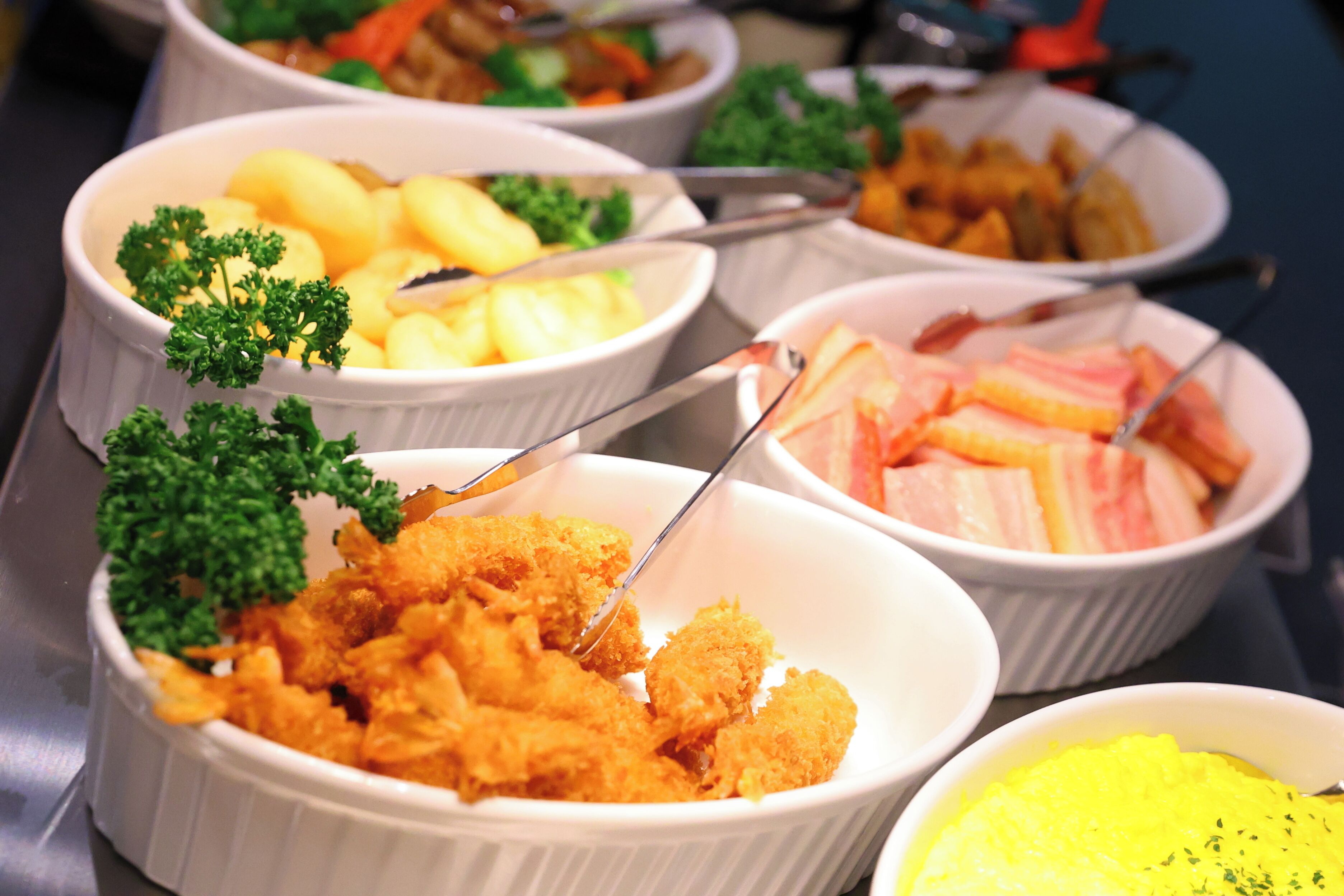 Buffet amb diferents plats, incloent aliments fregits, patates i un plat groc amb herbes.