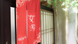 A traditional Japanese room with tatami flooring, a shoji screen door, and a red hanging banner with white text.