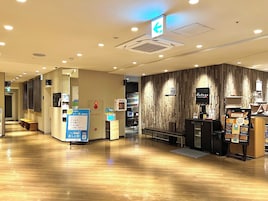 A modern interior with a wooden wall, a reception desk, and a vending machine.