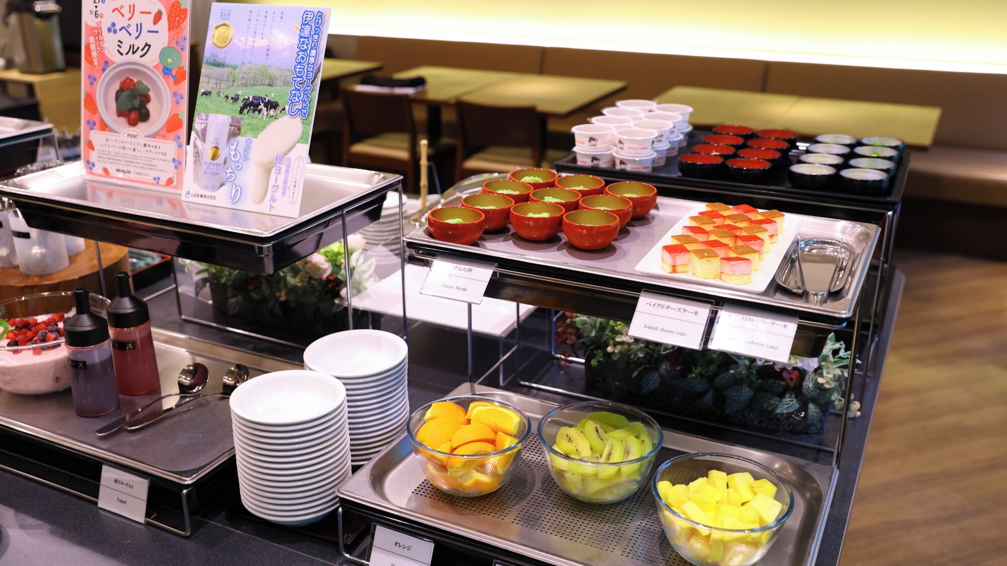 A buffet with various food items including fruit, cakes, and a sign indicating a 'baked cheese cake'.