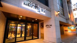 A hotel entrance with a glass door, signage indicating 'Hotel Darby Inn', and a 'Shiseido' advertisement on the wall.