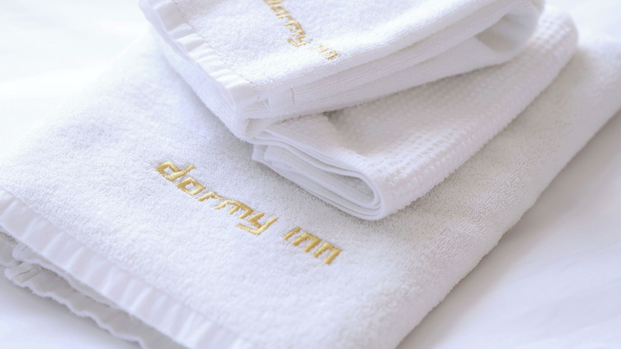 A stack of white towels with embroidered text.
