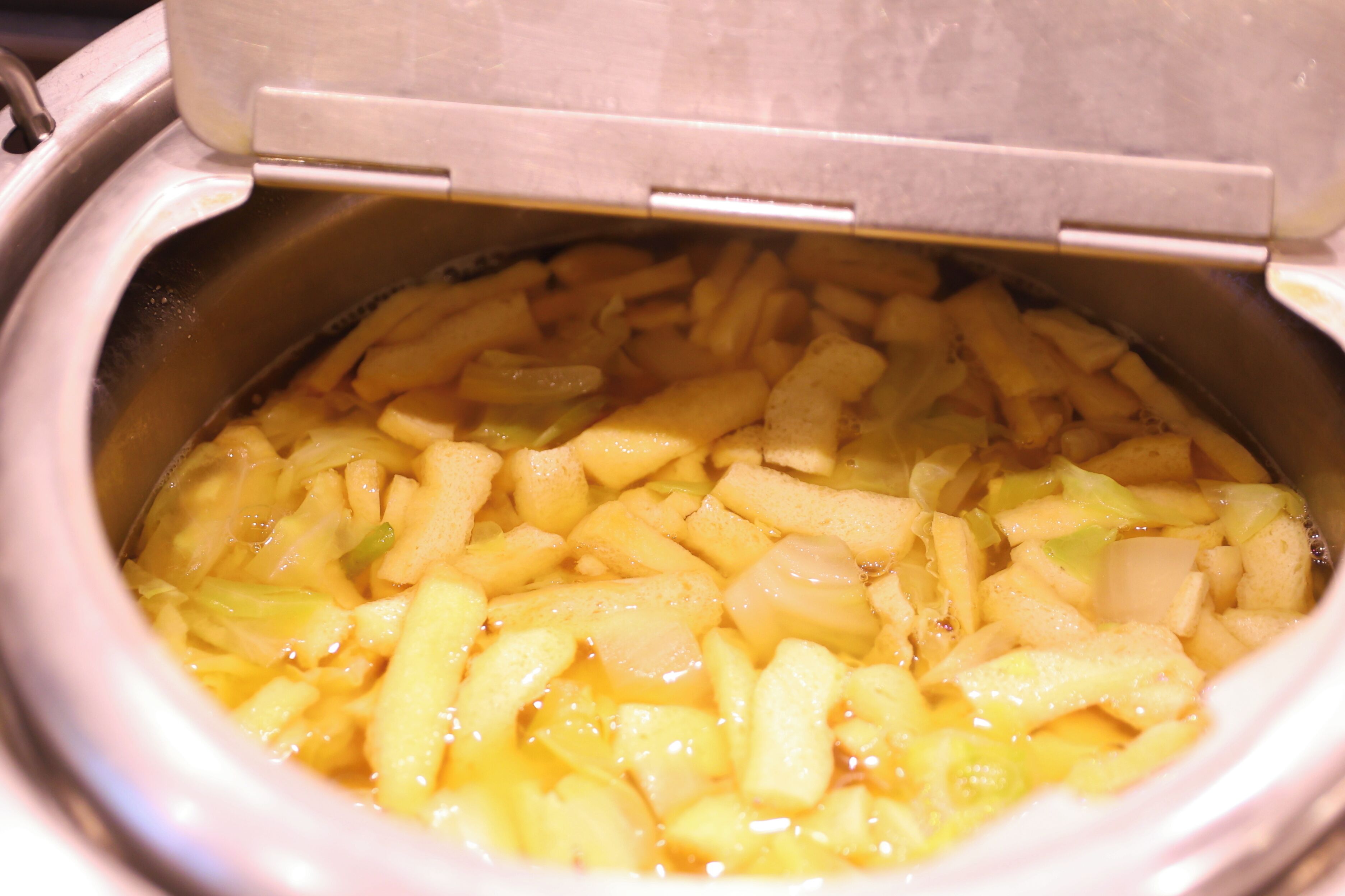 A slow cooker filled with French fries and vegetables.