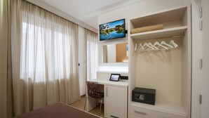 A hotel room with a bed, a desk with a computer, a TV, a wardrobe, and a window with curtains. - La Casa del Turista (Gallipoli)