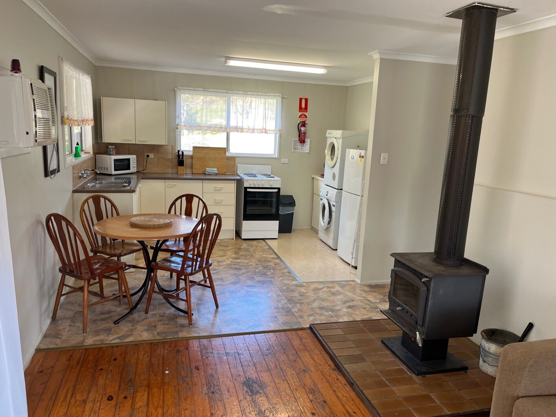 A compact kitchen with a dining area, a stove, and a washing machine.