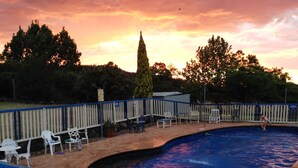 A swimming pool with a blue deck, surrounded by a white fence and various chairs. - Bestbrook Mountain Resort (Tregony)