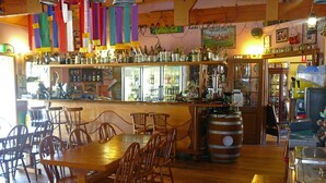 A bar area with wooden chairs and tables, a large barrel, and shelves with bottles. - Bestbrook Mountain Resort (Tregony)
