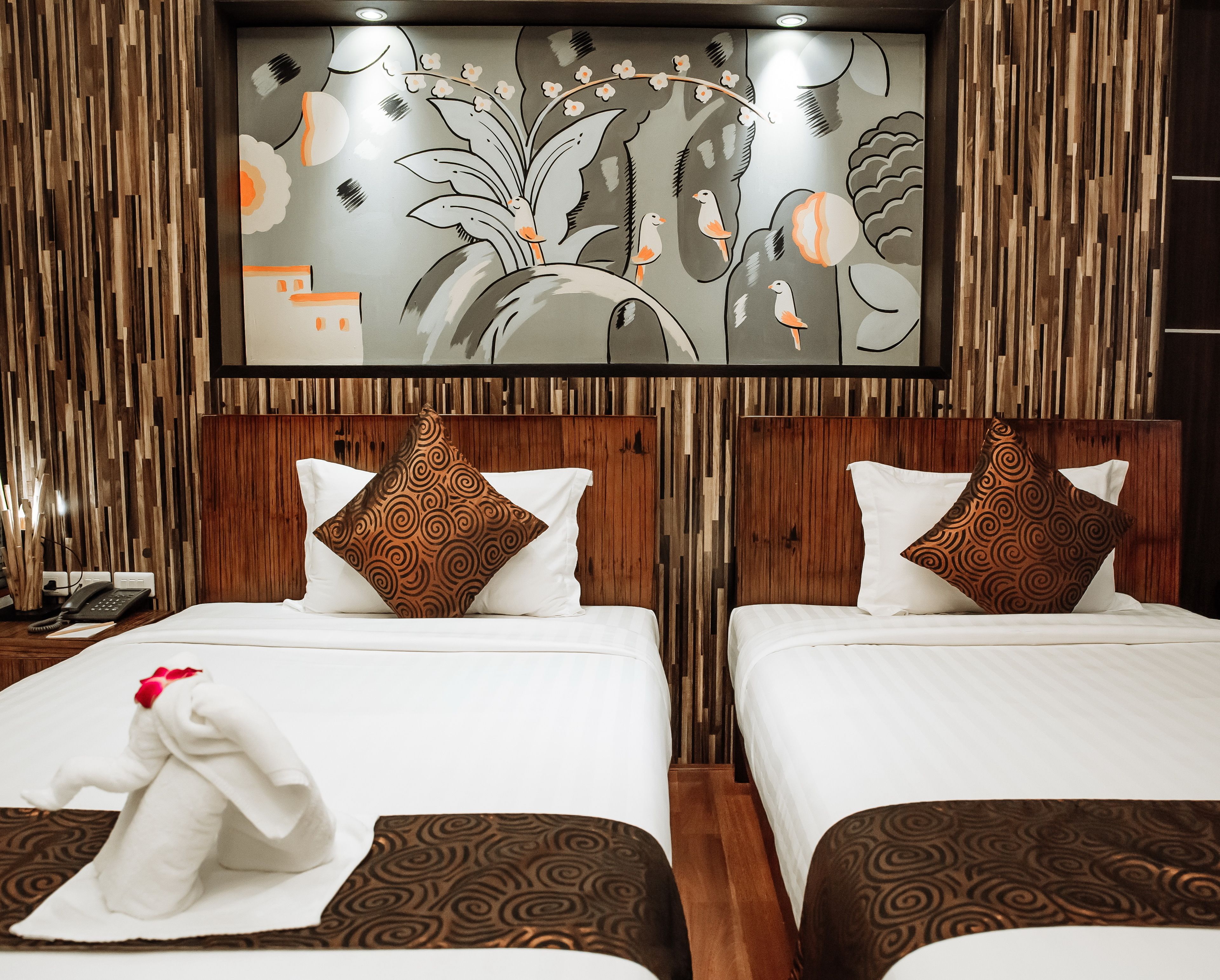 Habitación de hotel con dos camas, cada una con cabecero de madera y un gran mural en la pared.