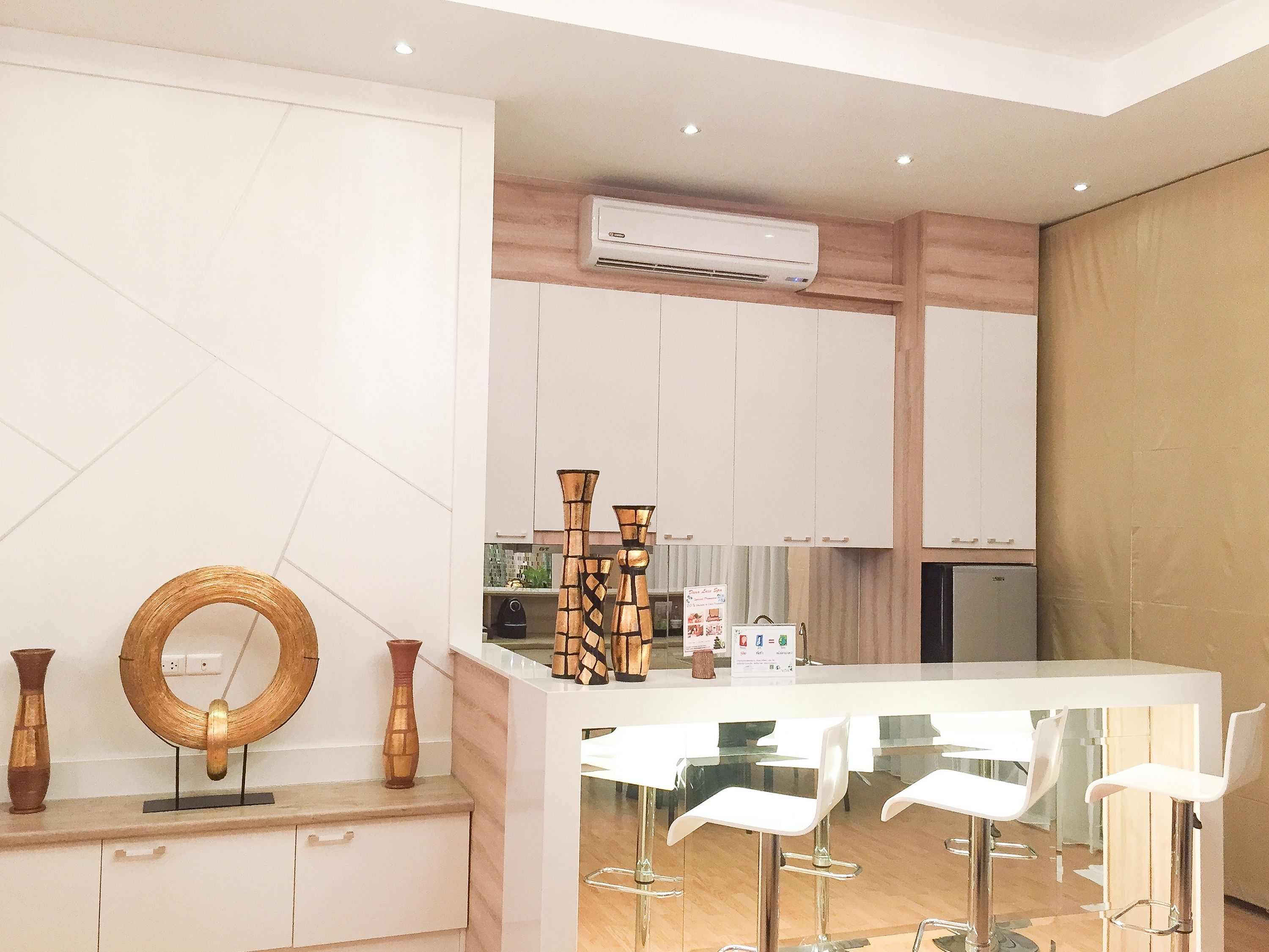 A modern kitchen with white cabinets, a built-in stove, and a white dining area with bar stools.