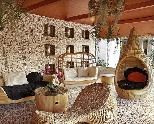 A room with a mosaic wall, wicker furniture, and hanging plants.