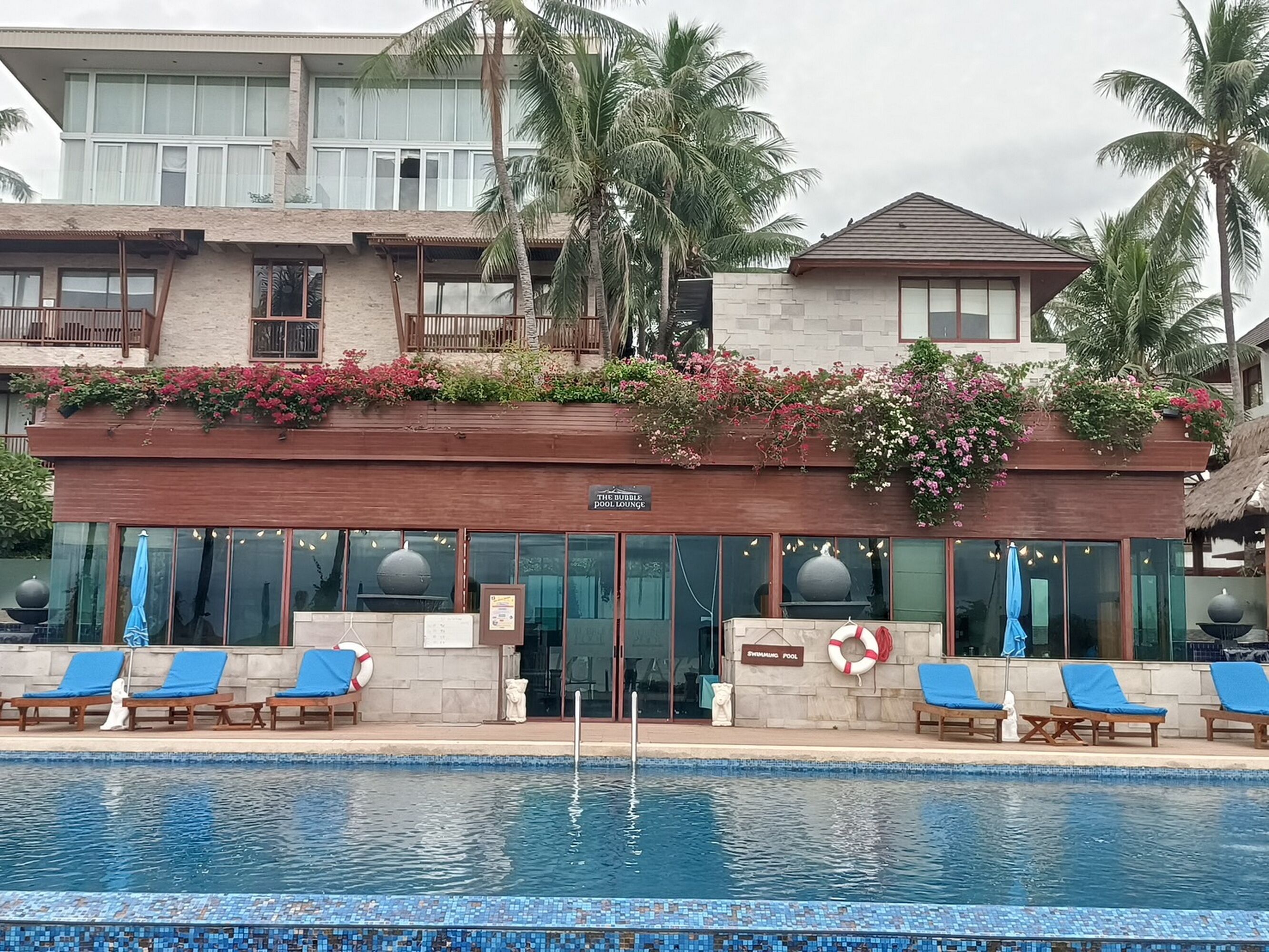 A hotel with a pool area, featuring lounge chairs and a sign indicating a swimming pool.
