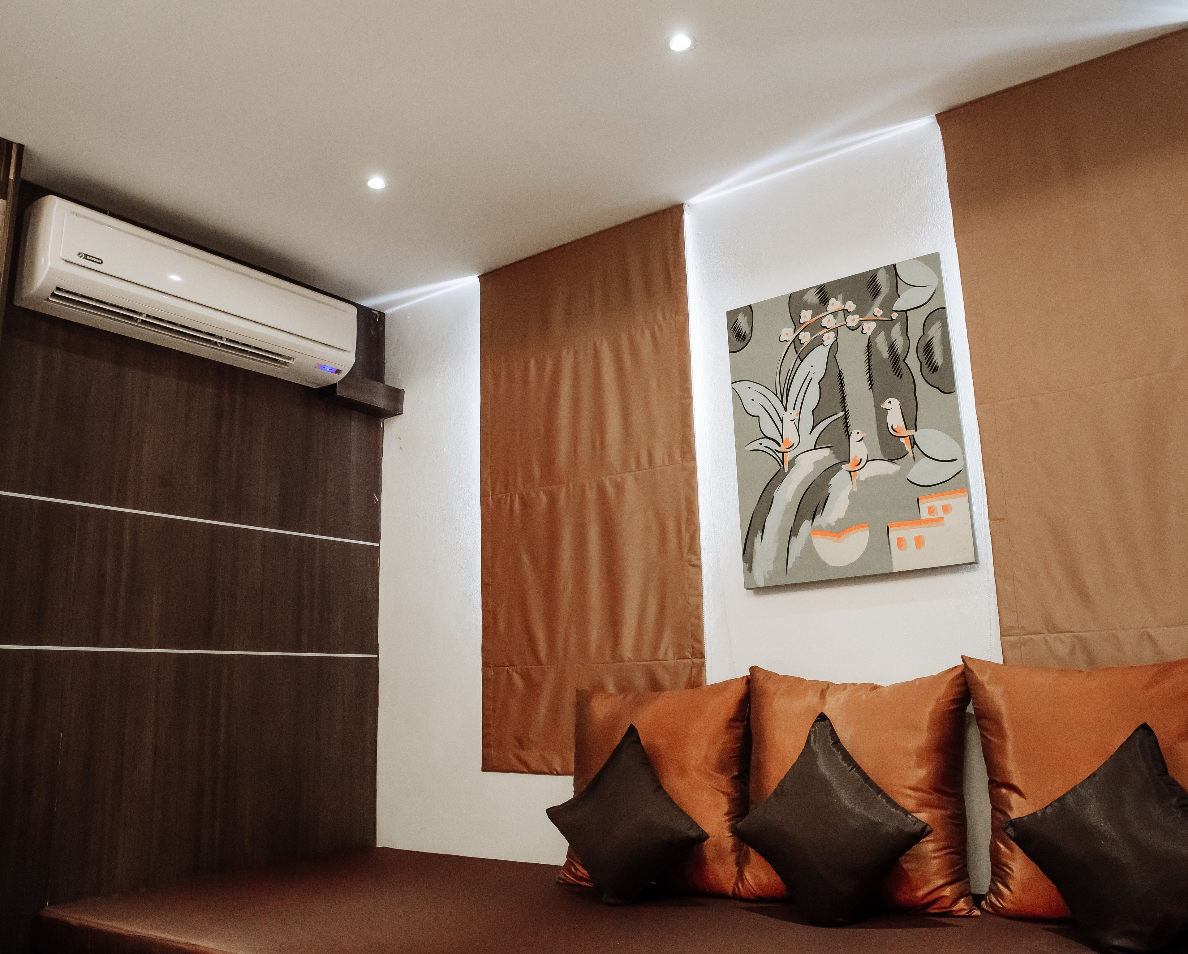 Una habitación moderna con un sofá de cuero marrón, aire acondicionado instalado en la pared y un cuadro colgado.