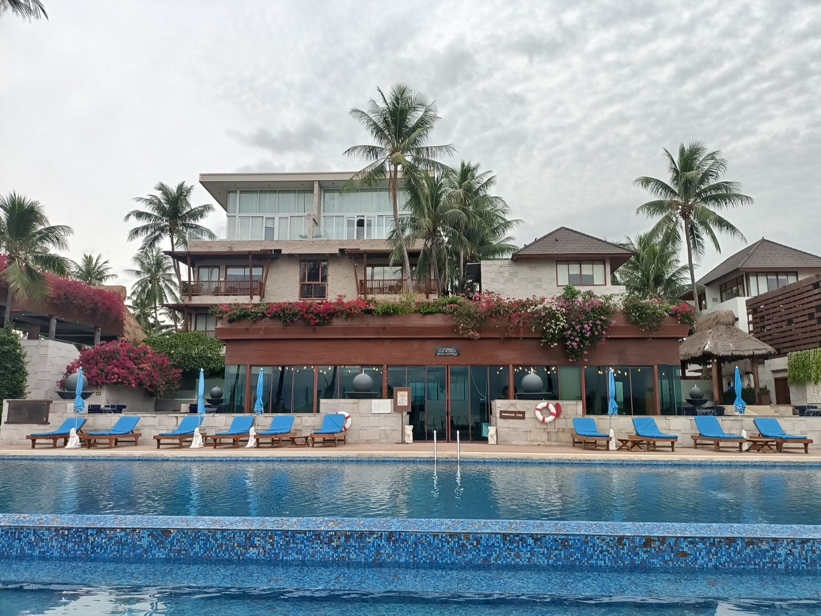 Un complexe hôtelier doté d’une piscine, de chaises longues et de palmiers.