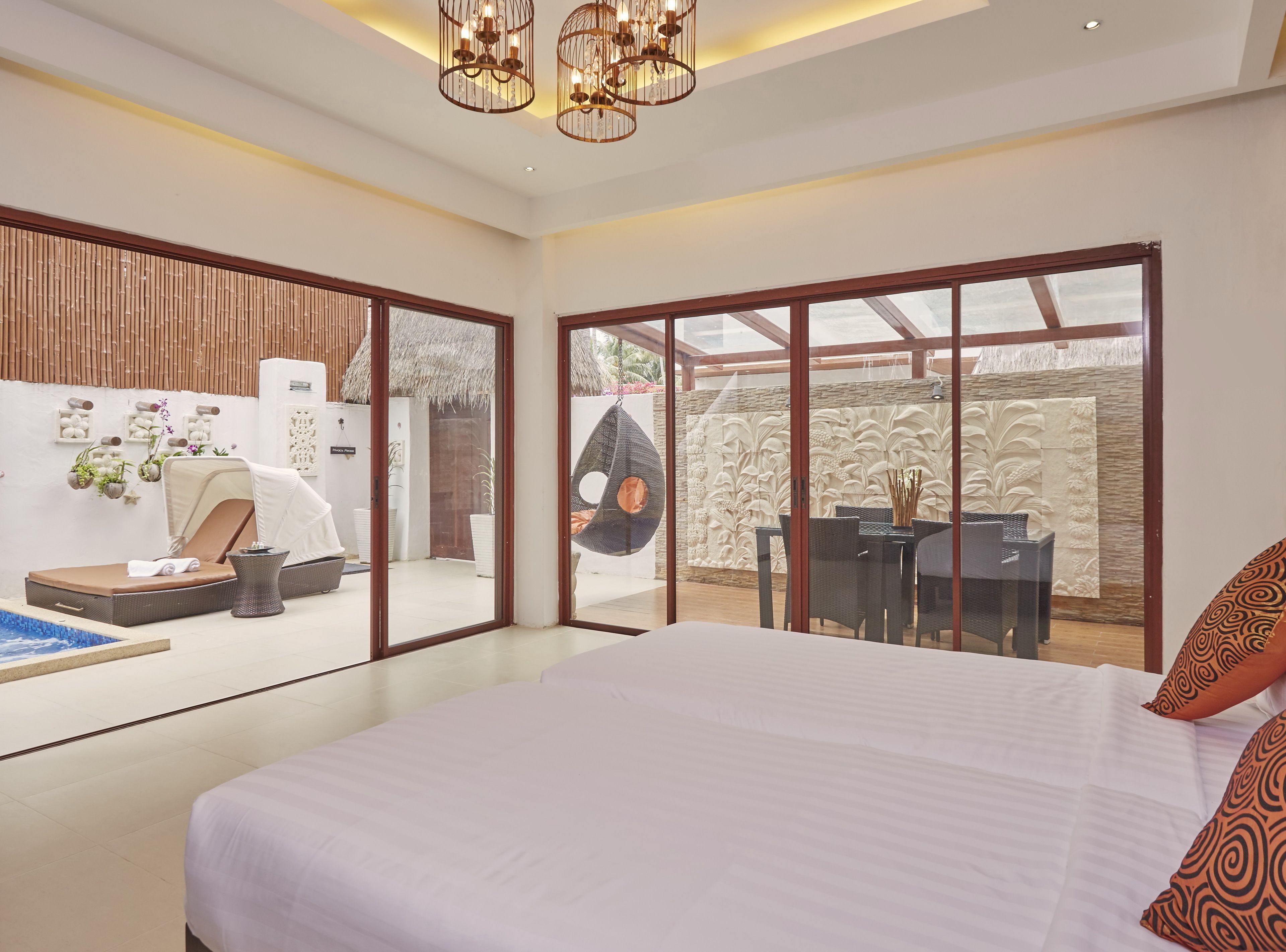 A modern bedroom with a large bed, a dining area, and a view of the outdoor space.