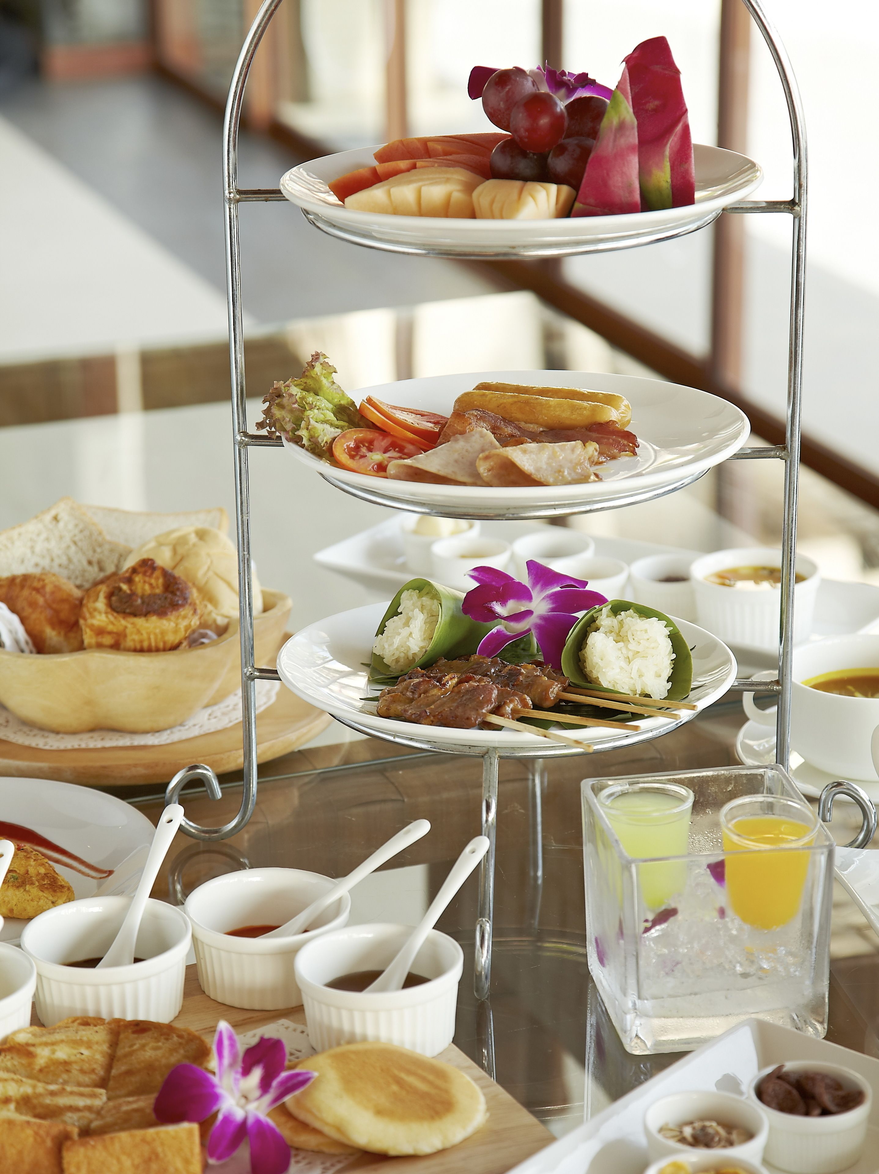 A three-tiered serving tray with various breakfast items including toast, eggs, and fruit.