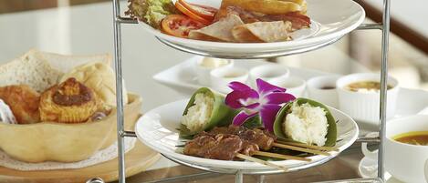 A three-tiered serving tray with various breakfast items including toast, eggs, and fruit.