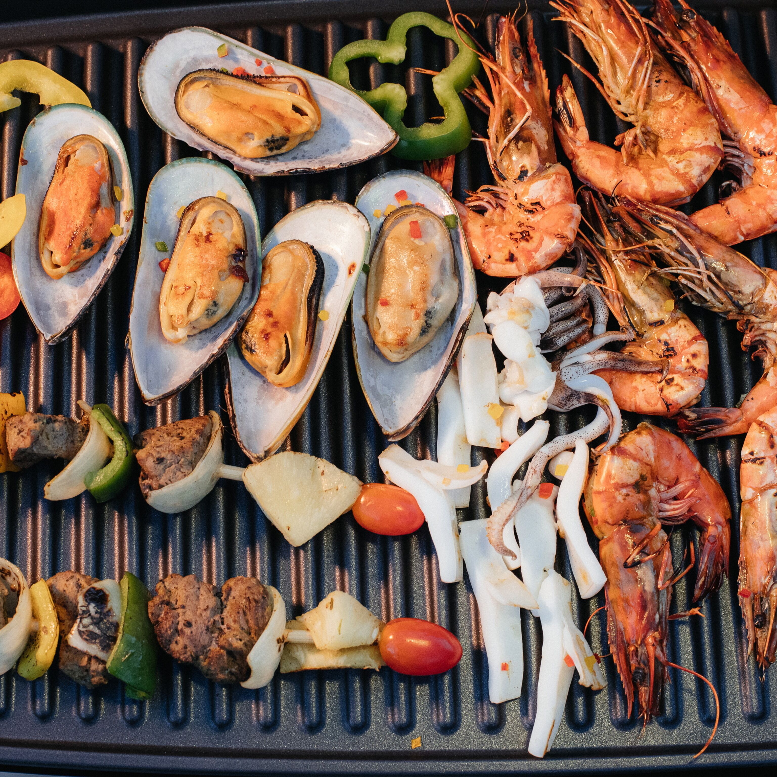 Un plat grillé composé de fruits de mer, notamment de crevettes, de moules et de calamars.
