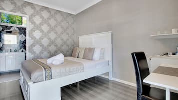 A bedroom with a bed, a desk, and a chair.