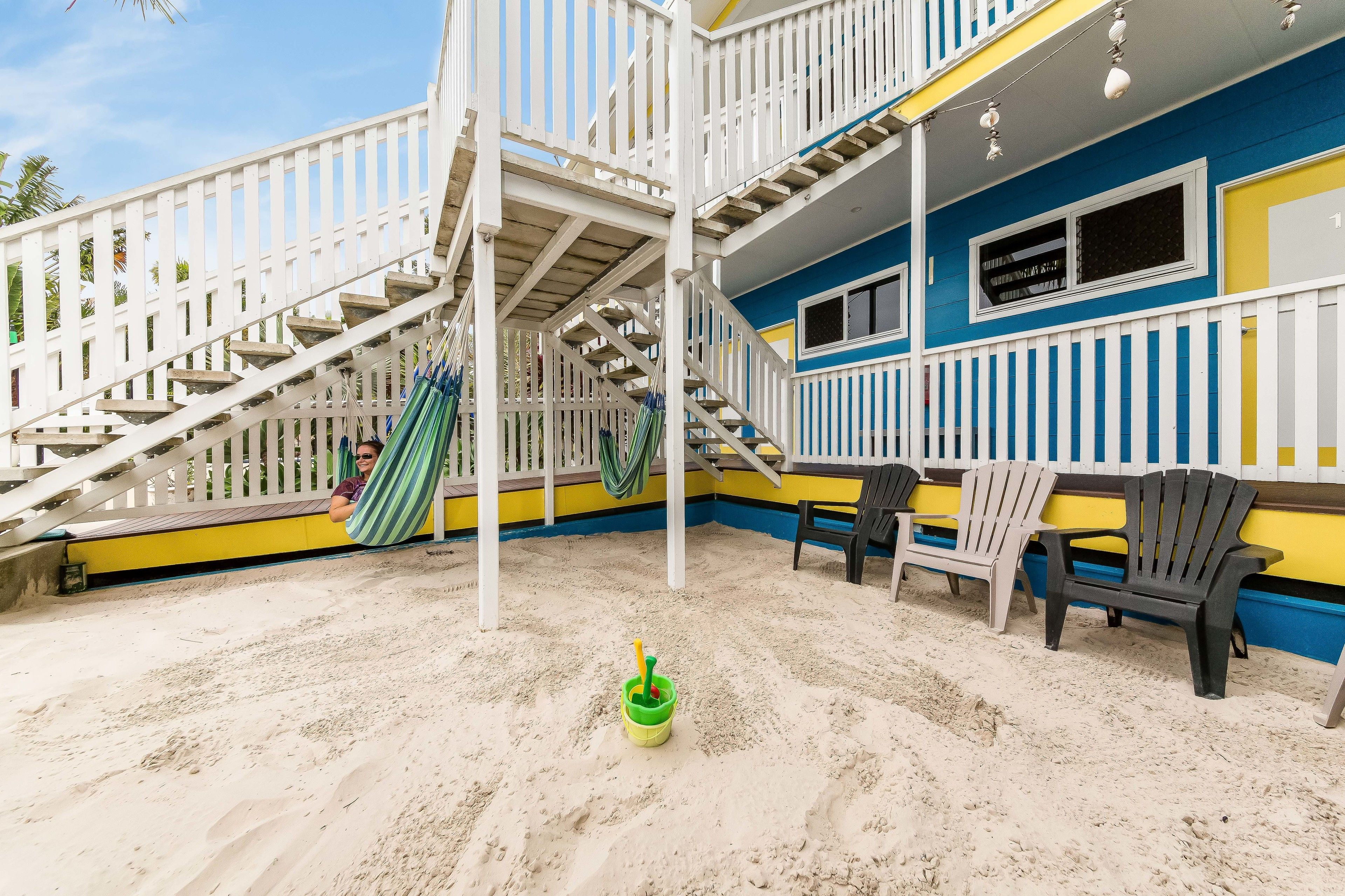 A multi-level outdoor deck with a staircase, a hammock, and a green bucket with a yellow handle.
