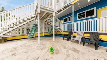 A multi-level outdoor deck with a staircase, a hammock, and a green bucket with a yellow handle.