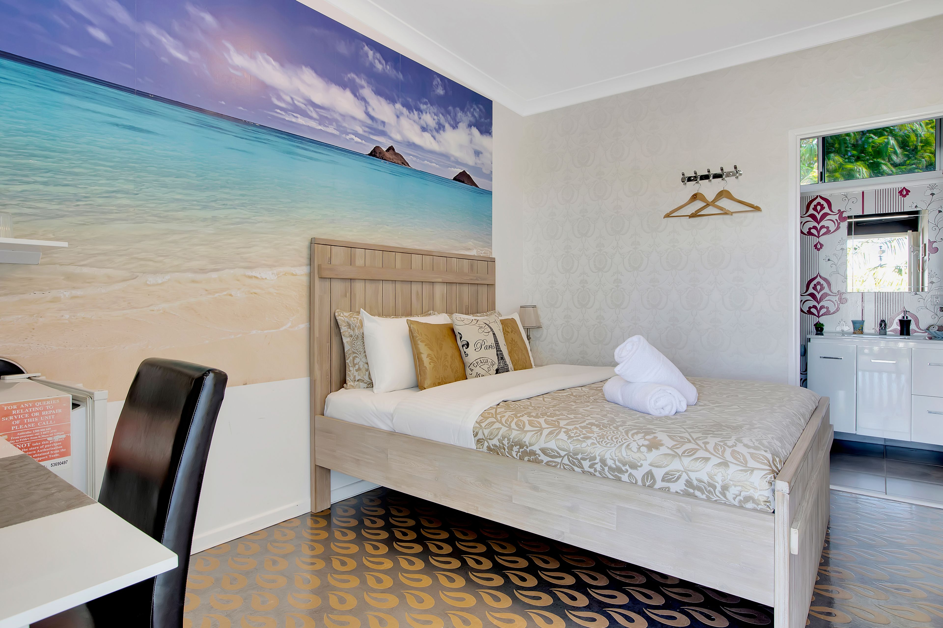 A hotel room with a bed, a desk, and a view of the ocean.