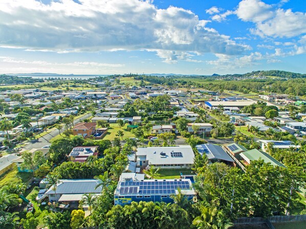 An aerial view of a residential area with houses, solar panels on rooftops, and lush greenery.