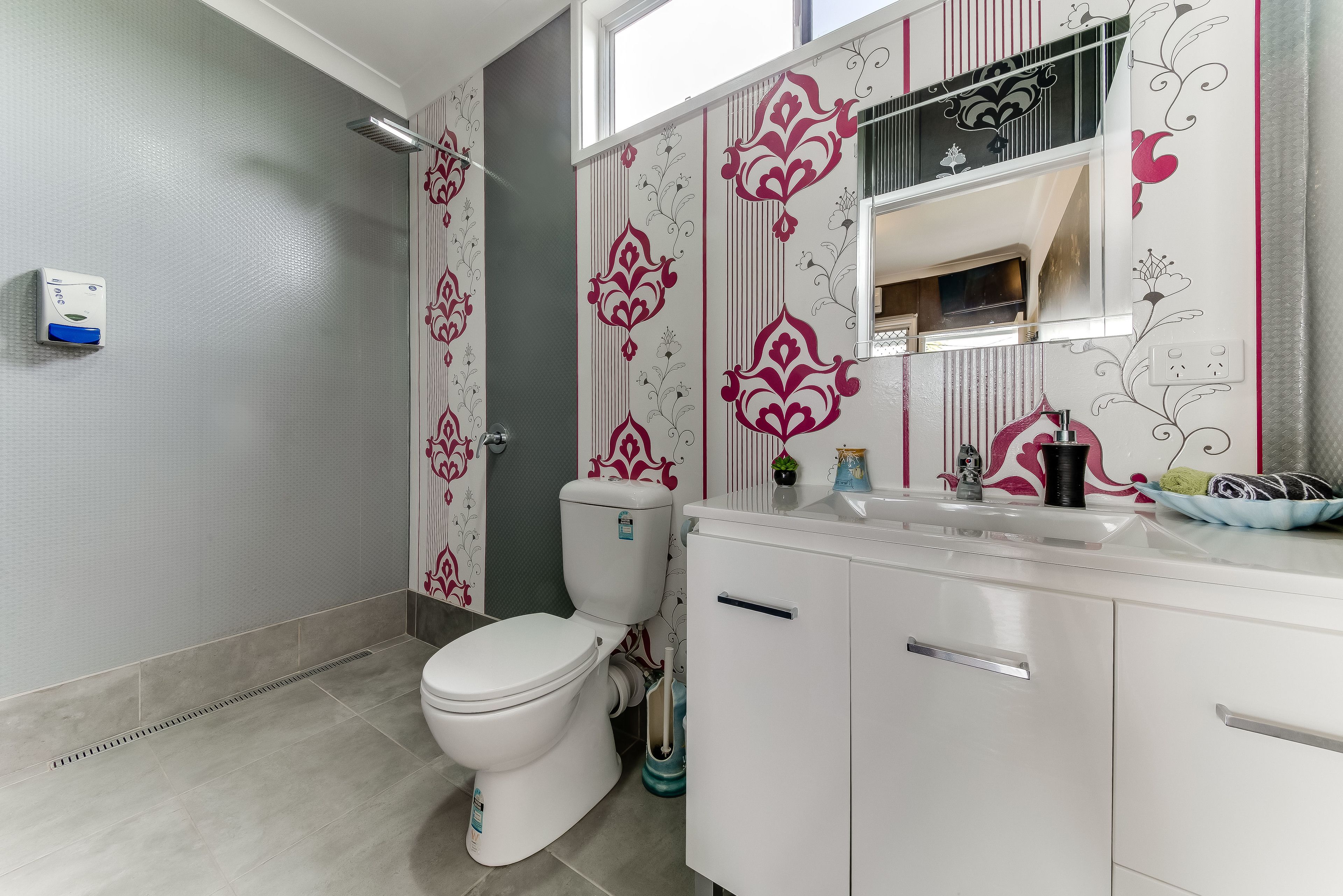 A modern bathroom with a toilet, vanity, and a shower area.