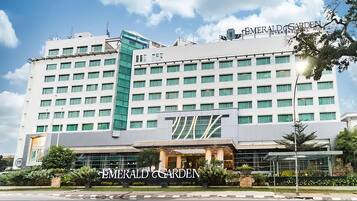Un hôtel à plusieurs étages, reconnaissable à son enseigne bien visible indiquant : « Emerald Garden International Hotel ».