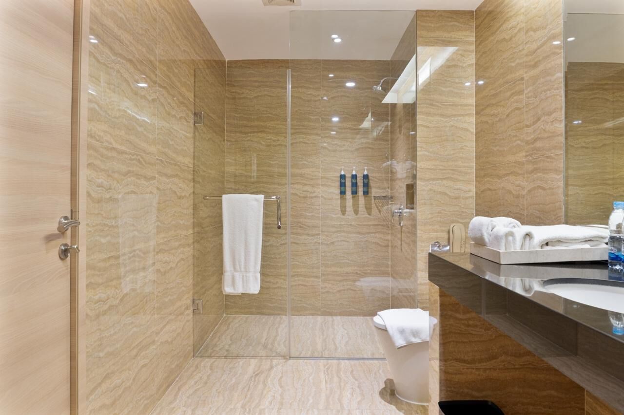 A modern bathroom with a glass-enclosed shower, a vanity with a mirror, and a towel rack.