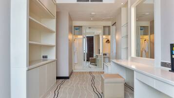A hotel corridor with a vanity area, a mirror, and a bench.