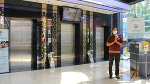 A hotel lobby with a modern design, featuring a large digital screen, a reception area, and a sign for a spa.