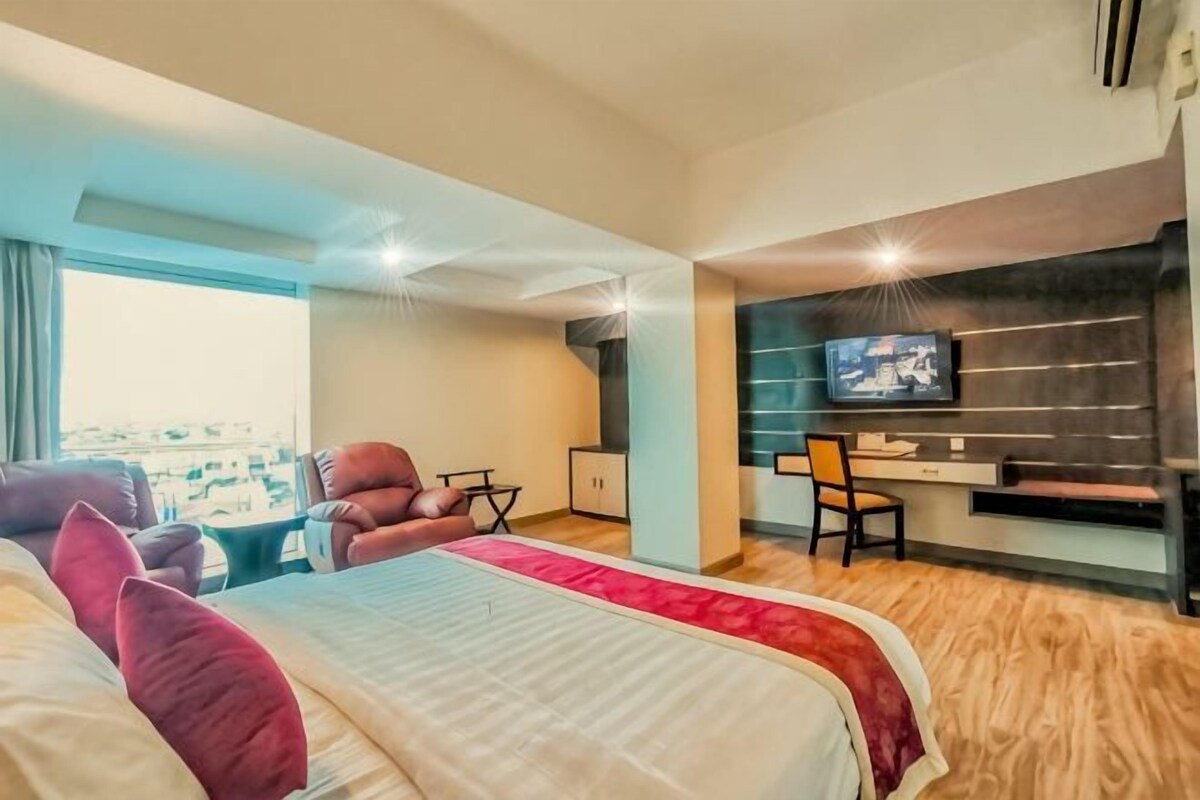 Habitación de hotel con una cama grande, un escritorio, una silla y un televisor.