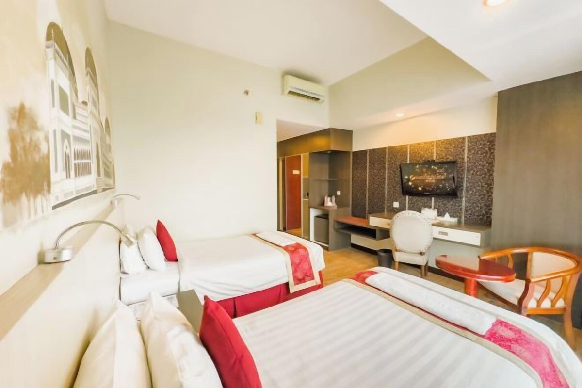A hotel room with two beds, a desk, a chair, and a television.