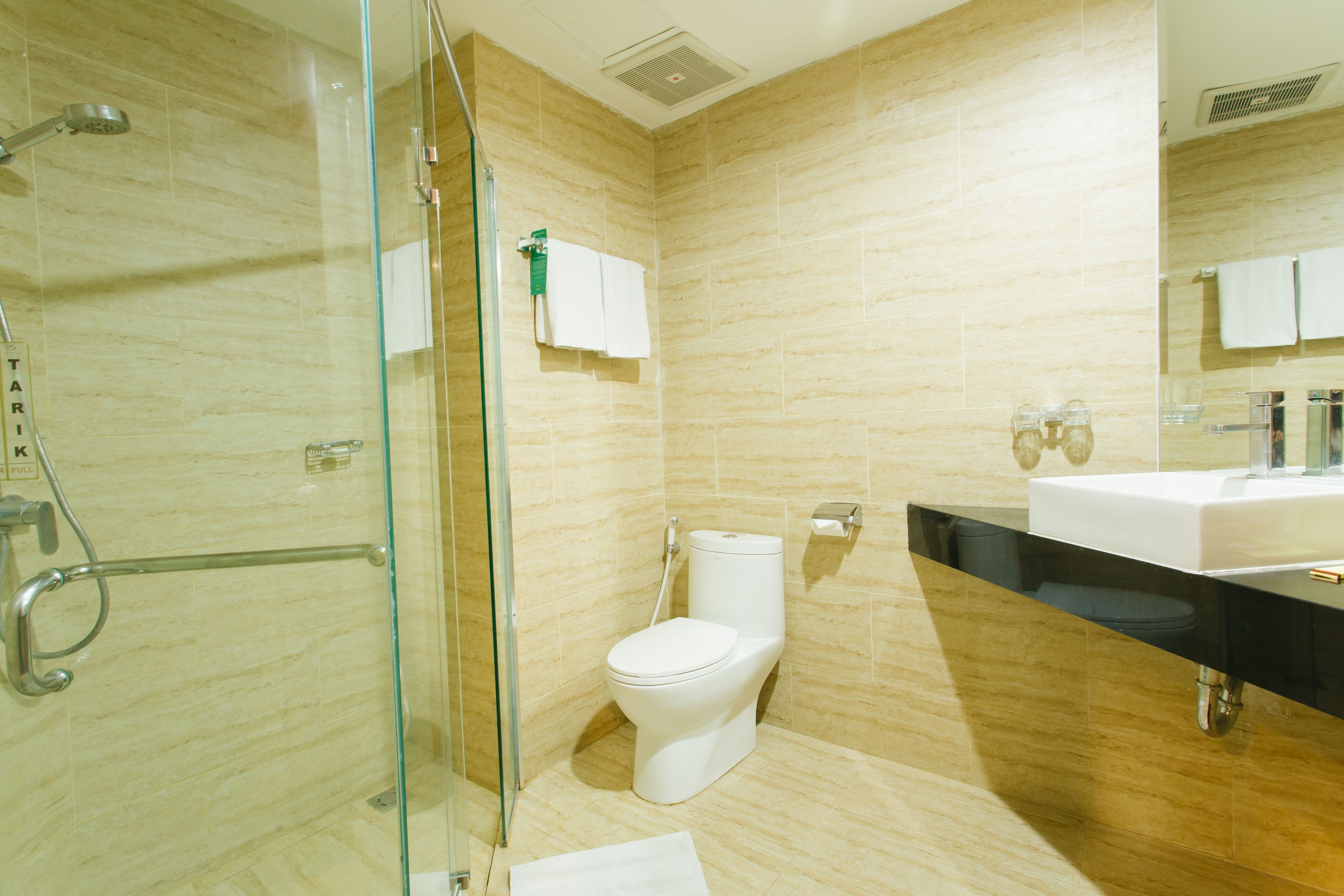 A modern bathroom with a glass shower enclosure, a white toilet, and a black countertop with a sink.
