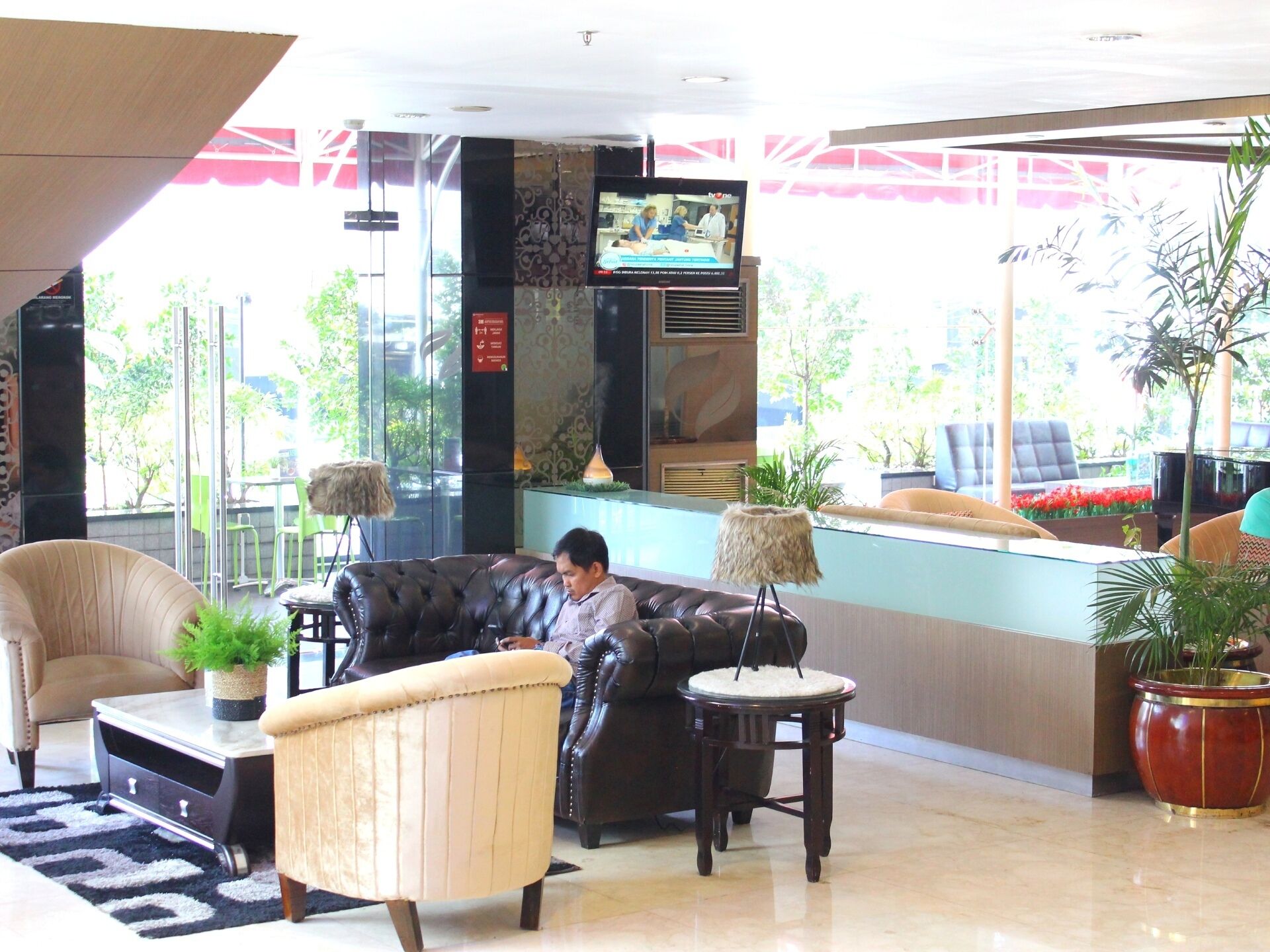 A lobby with leather sofas, a reception desk, and potted plants.