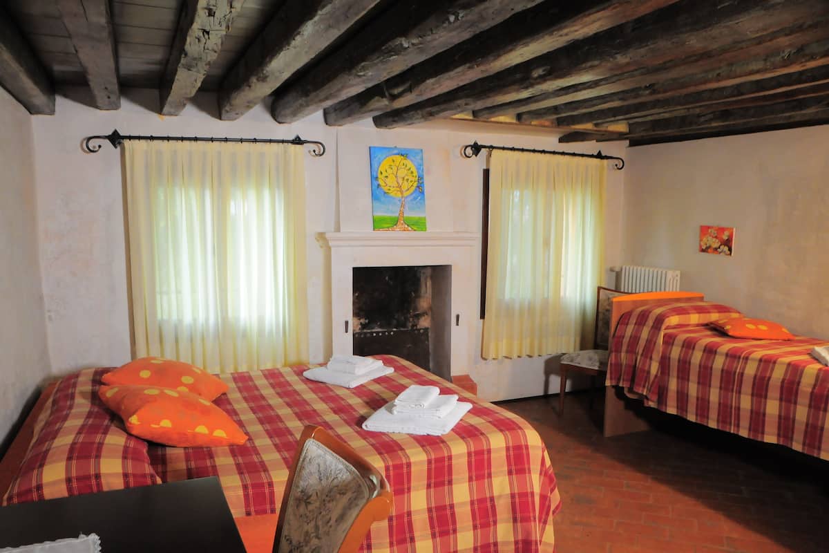 Een kamer met twee bedden, een open haard en een schilderij aan de wand.