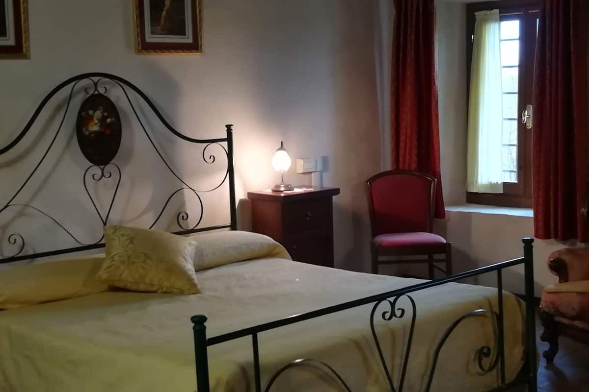 Een kamer met een bed, bureau, stoel en een raam met gordijnen.