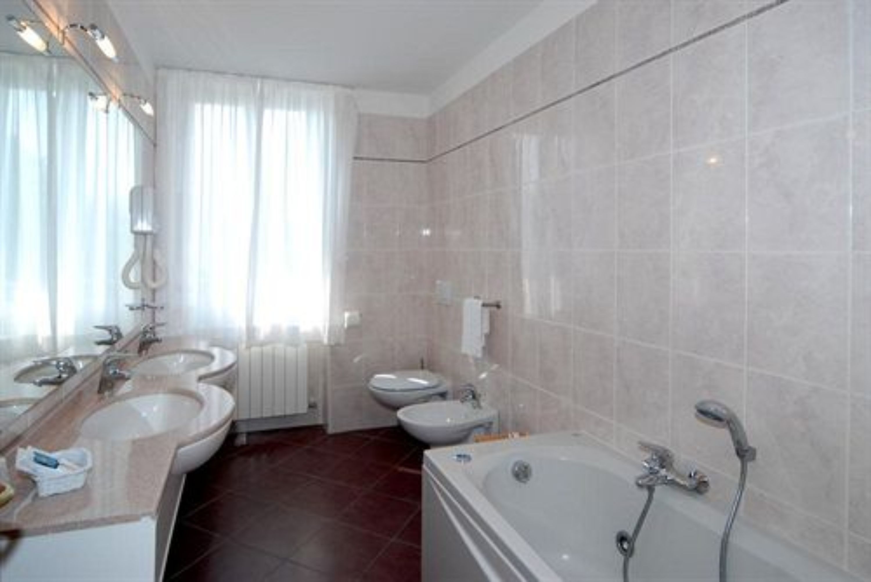 A modern bathroom with two sinks, a toilet, and a bathtub.
