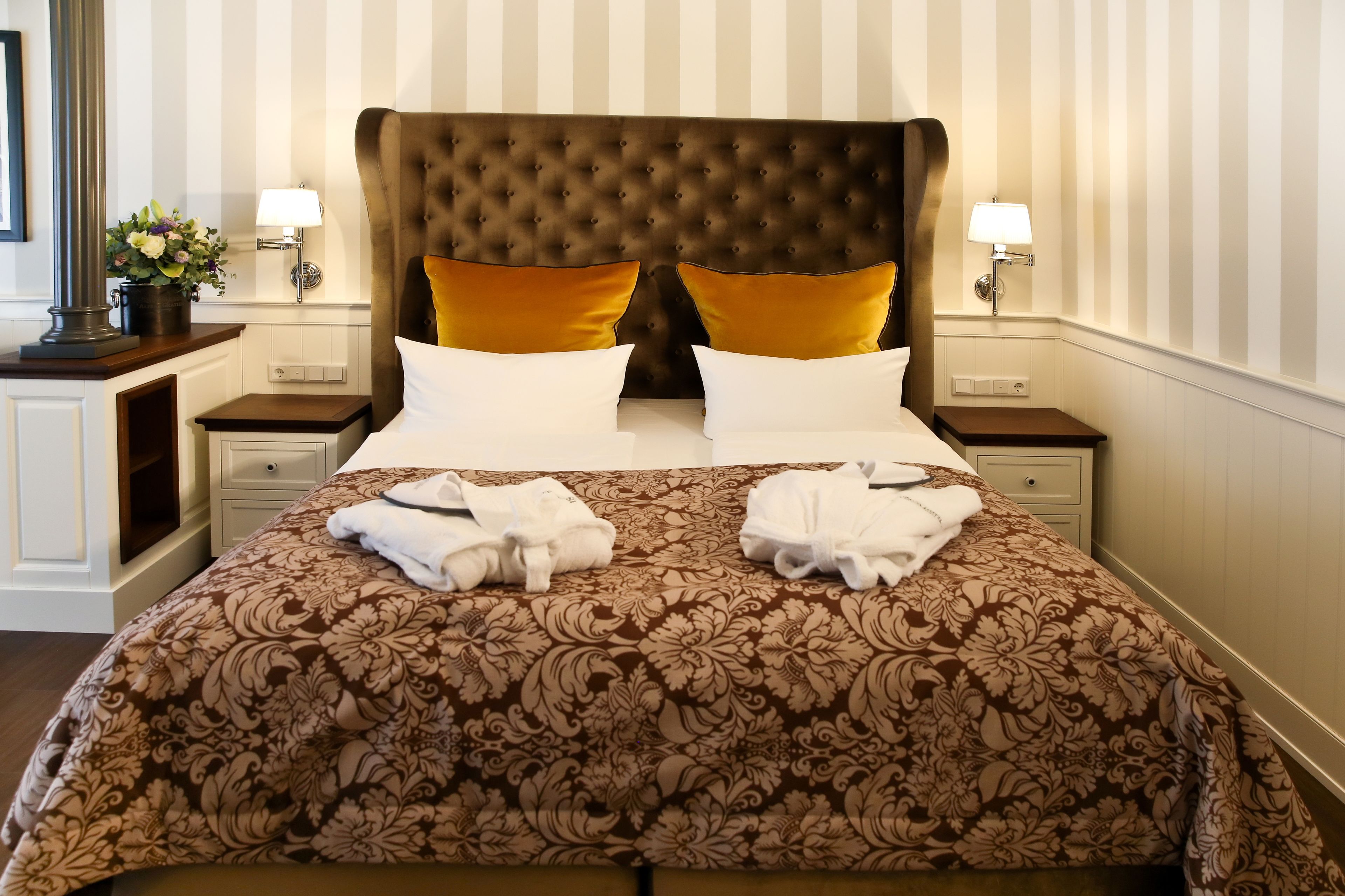 Una habitación de hotel con una cama grande, dos mesitas de noche y una lámpara de pared.