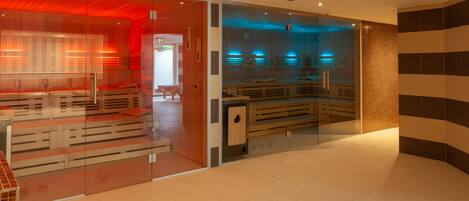 A modern spa area with glass partitions, wooden benches, and a tiled floor.