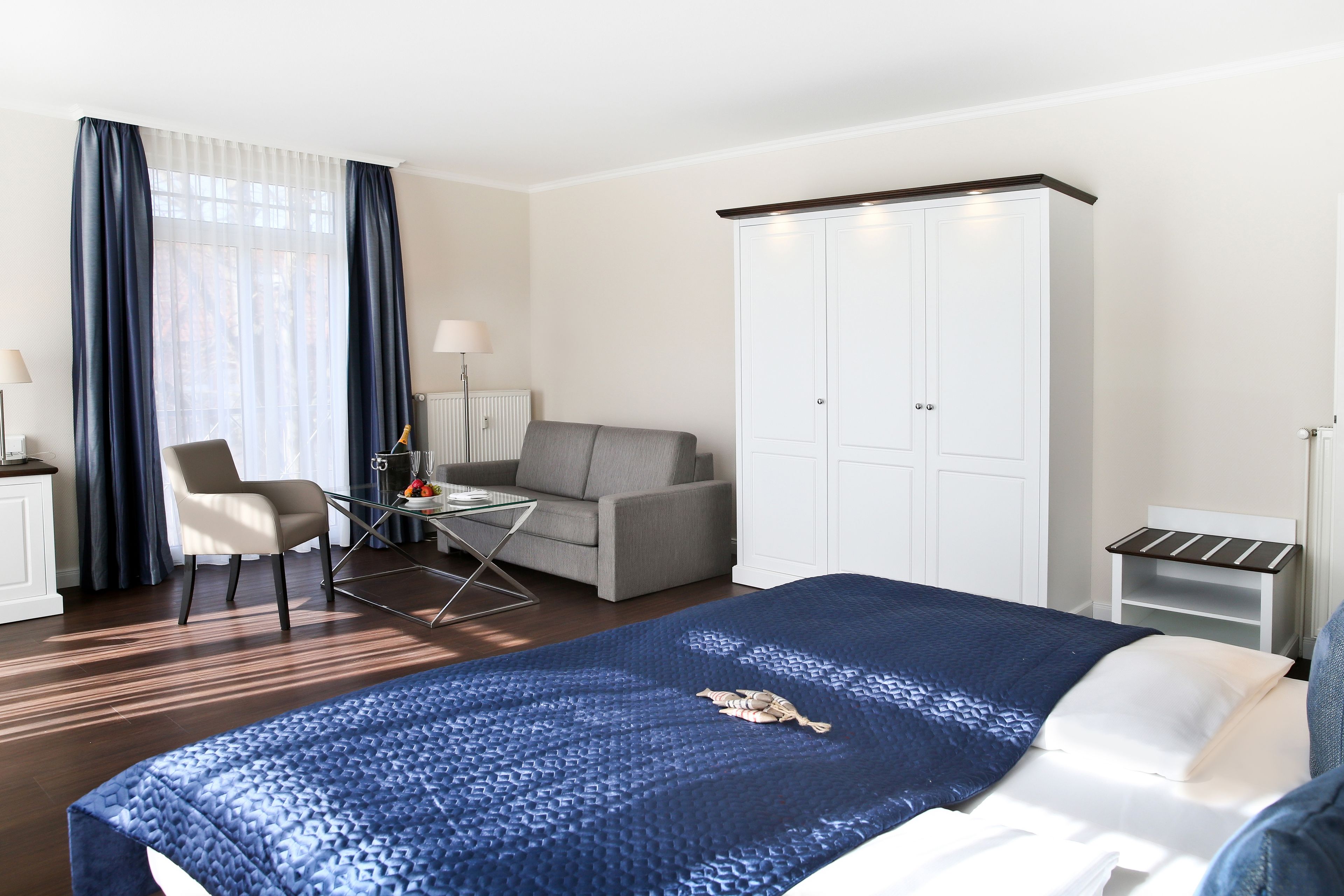 A hotel room with a bed, a desk, a chair, a sofa, and a wardrobe.