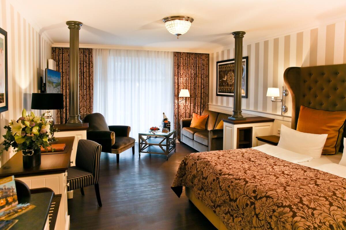 Una habitación de hotel con una cama grande, un sofá, un escritorio con lámpara y una silla.