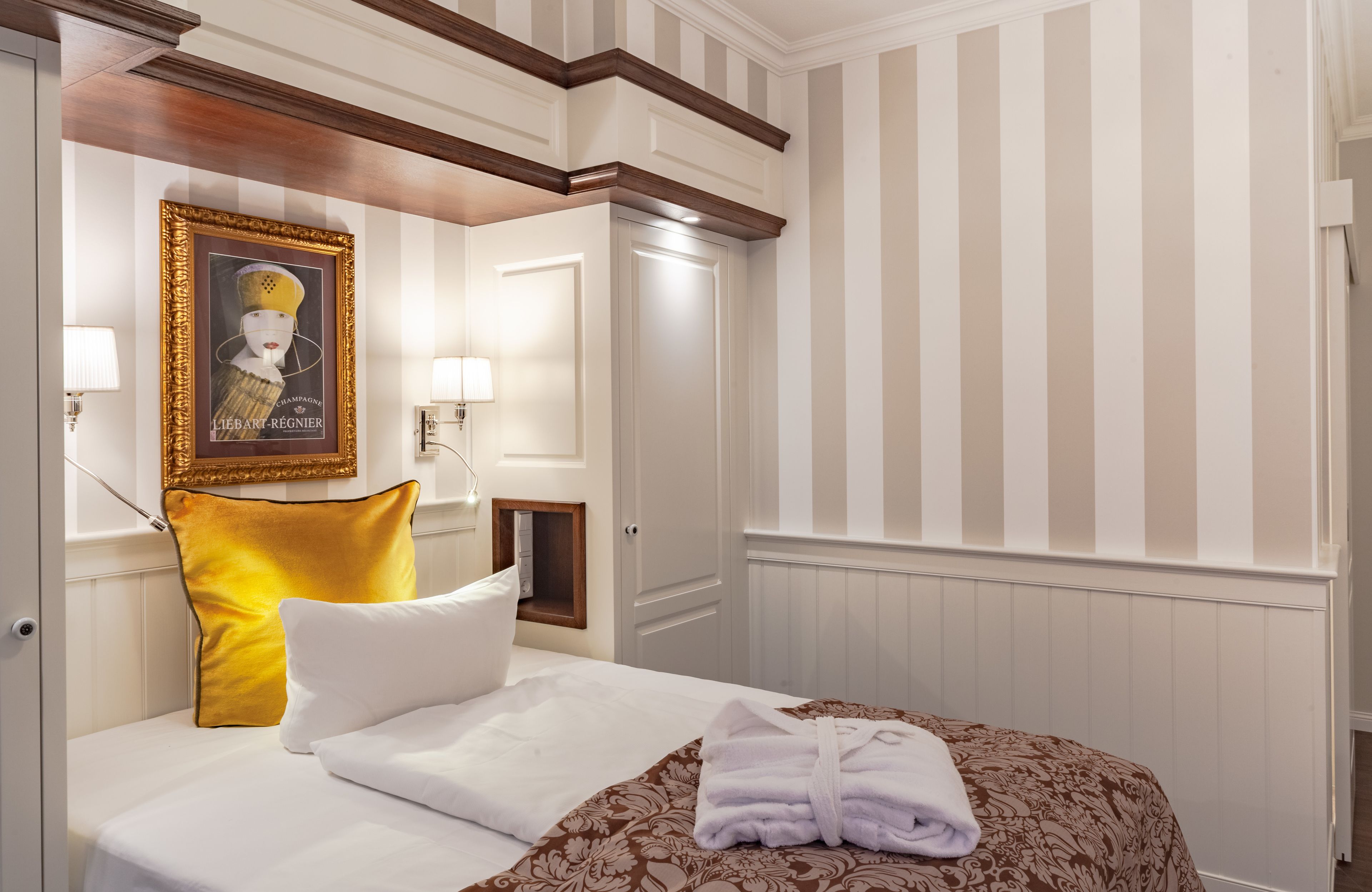 Quarto de hotel com cama, um quadro, uma luminária e uma porta.