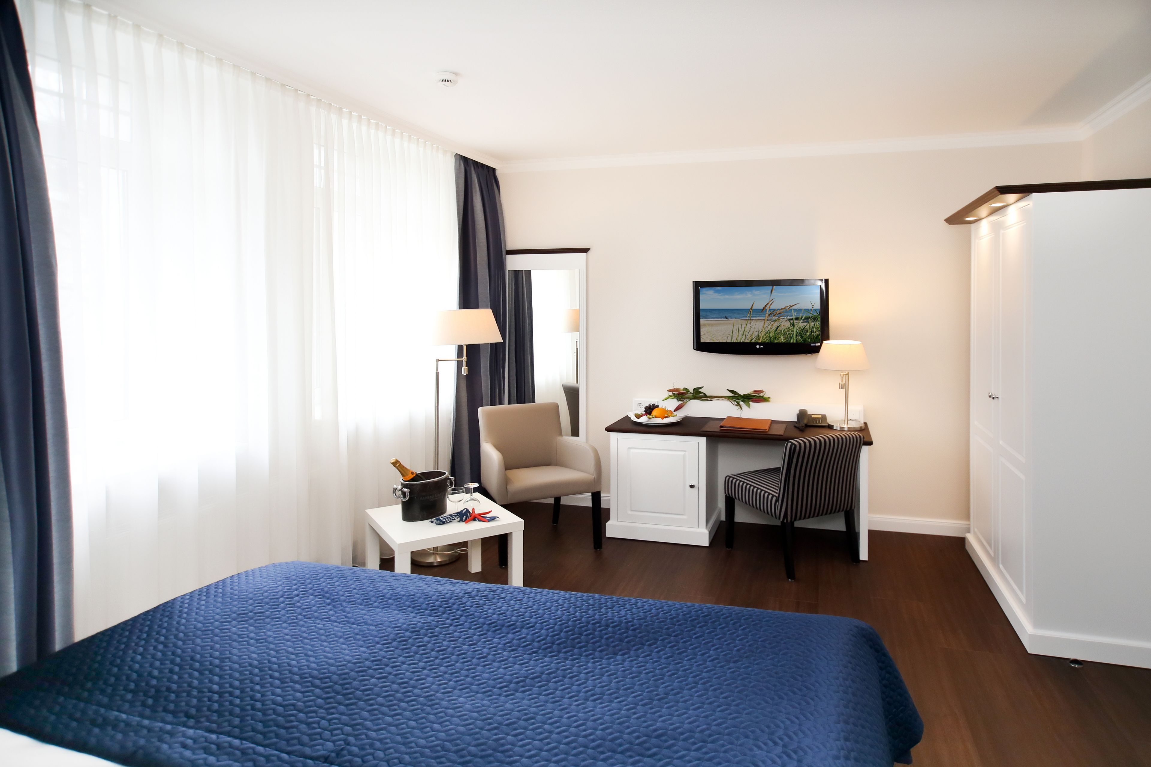 Une chambre d’hôtel comprenant un lit, un bureau, une chaise, une télévision et un placard.