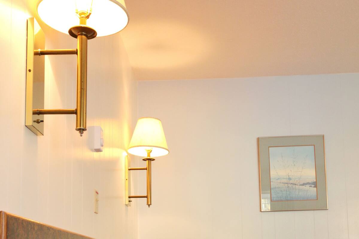 Habitación de hotel con una cama, dos lámparas de pared y un cuadro en la pared.