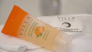 Une bouteille de shampoing après-shampoing de la gamme Villa Collection, posée sur une serviette blanche.