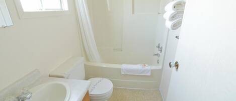 A bathroom with a sink, toilet, bathtub, and a shower curtain.