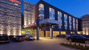 A Hampton hotel with a modern facade, multiple parking spaces, and a well-lit entrance. - Hampton by Hilton Warsaw Airport (Warsaw)